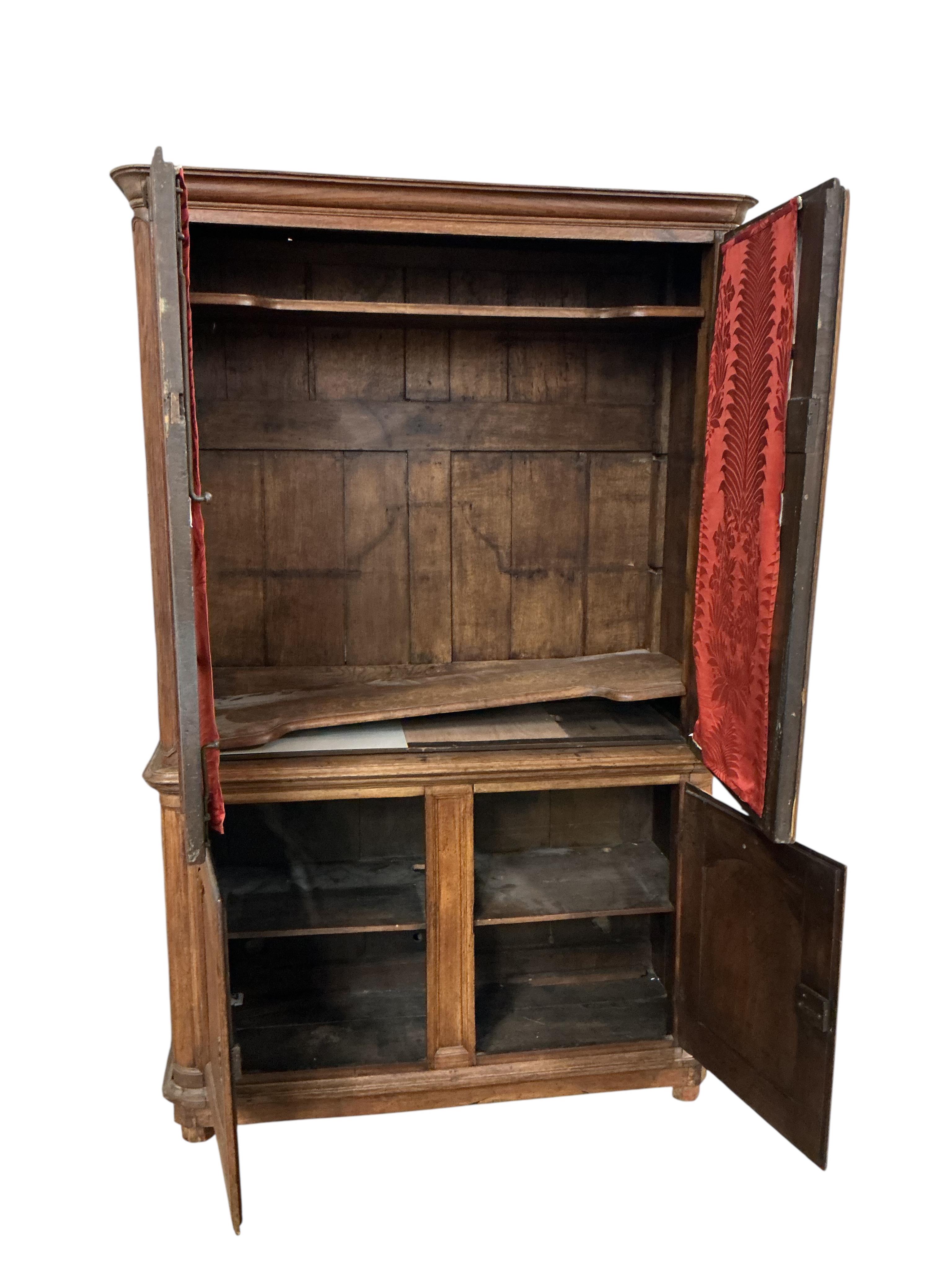 An early 19th century French Burgundian oak cabinet with two glazed doors over two arched panelled door, width 130cm, depth 49cm, height 206cm